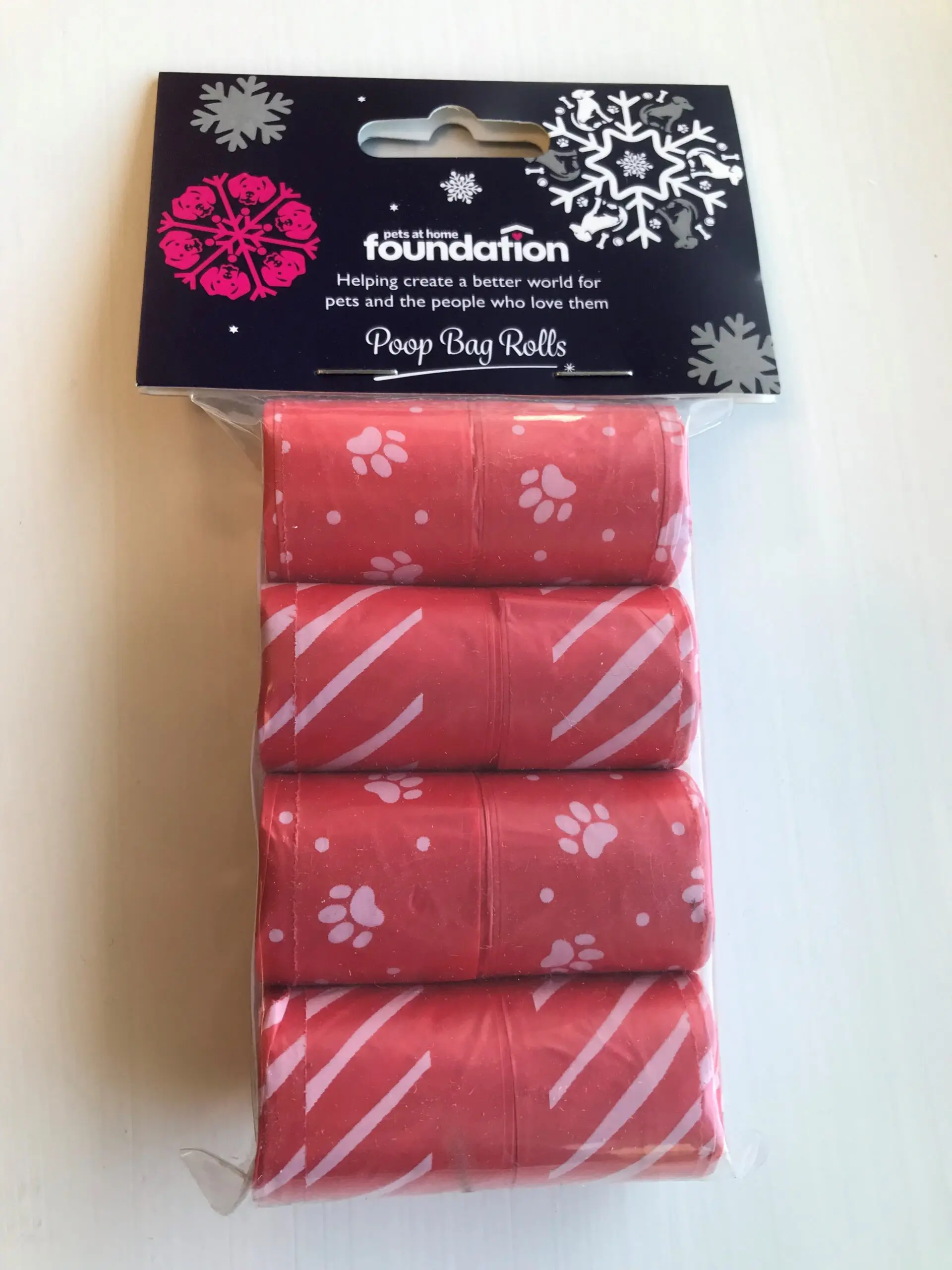 4 pack of red poop bag rolls with white paw print and stripe patterns