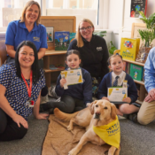 A group of people and a Pets As Therapy dog sitting in a school.