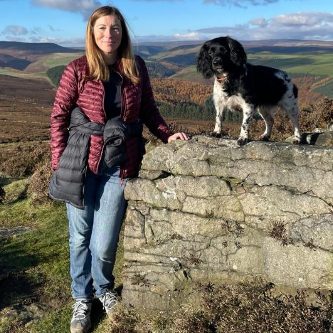 A person standing on a rock with their dog.